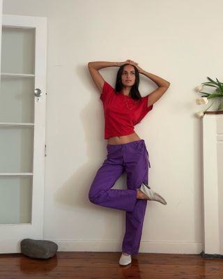 Bella Thomas wears purple sugilite pants with a red t-shirt.