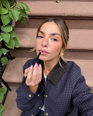 Content creator Kit Keenan reapplies her lip liner while wearing J.Crew's Short Barn Jacket