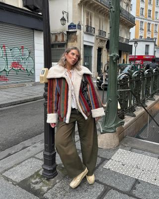 Woman wears striped coat, green jeans and yellow shoes