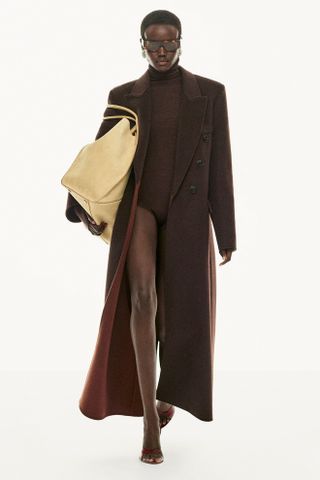 Model wears a chocolate brown coat and butter yellow bag of the Victoria Beckham PreFall 2025 Collection