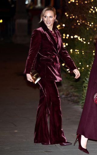 Zara Tindall wears a gold Strathberry bag and a burgundy velvet Veronica Beard pantsuit