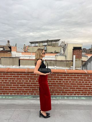 Eliza Huber wearing a black boatneck T-shirt and red velvet Blazé Milano midi skirt.