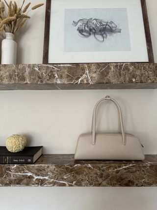 The oat Mercer Bag on a marble shelf next to a hard-cover book.