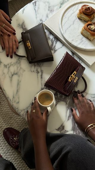 Brown nails on marble coffee table with Kelly handbags and coffee