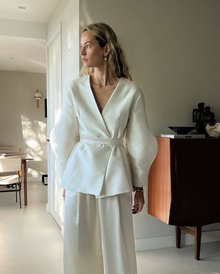 Anouk Yve wearing a cream satin belted evening jacket