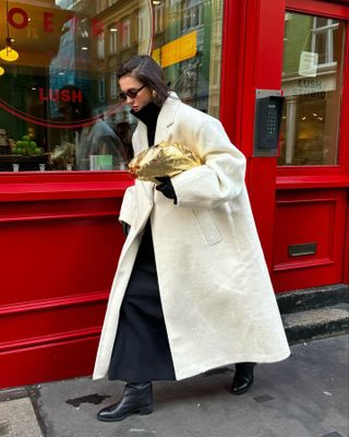 Woman wears cream coat, black maxi dress and black boots