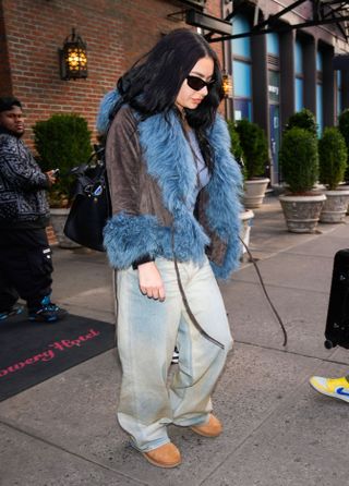 charlie xcx wearing uggs, wide-leg jeans and a blue furry jacket