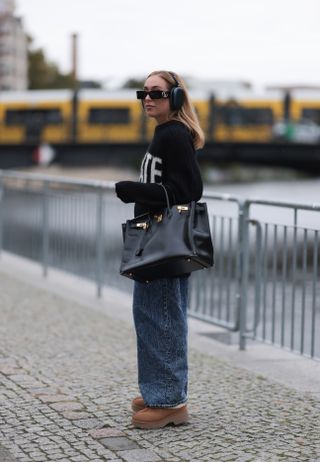 street style shot of baggy jeans worn with uggs and a birkin