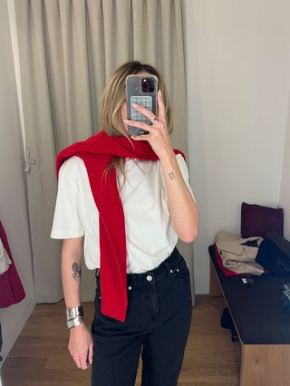 Eliza Huber in the dressing room at Madewell's new SoHo flagship in New York wearing a white T-shirt, black jeans, and studded ankle boots with a red sweater tied around her shoulders.