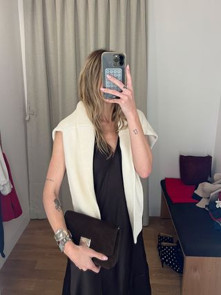 Eliza Huber in the dressing room at Madewell's new SoHo flagship in New York wearing a brown satin slip dress with a cream sweater around her shoulders, brown suede loafers, and a brown suede Agmes x Madewell bag.