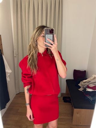 Eliza Huber in the dressing room at Madewell's new SoHo flagship in New York wearing a red jacket and skirt set.