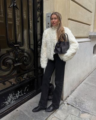 woman wearing white fuzzy coat with black jeans and loafers