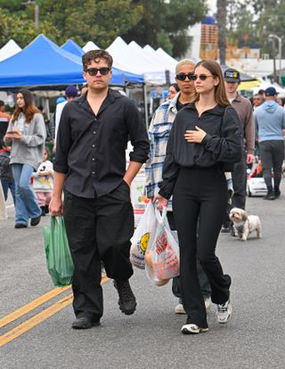 Barbara Palvin and Dylan Sprouse walk at a farmers market in Los Angeles in December 2024.