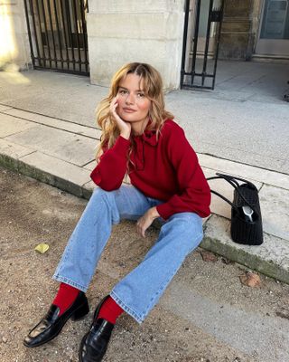 French woman wears a red sweater with red socks, loafers and jeans in Paris