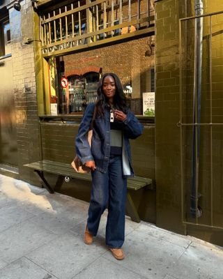 London woman wears dark wash jeans with a jean jacket, rugby shirt and moccasins.