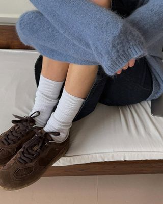 Woman wearing brown suede sneakers with white socks.