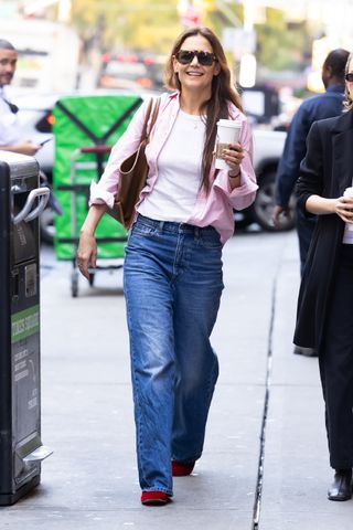 Katie Holmes is seen out and about on November 6, 2024 in New York, New York wearing a pink button-down shirt, jeans, and burgundy slippers.