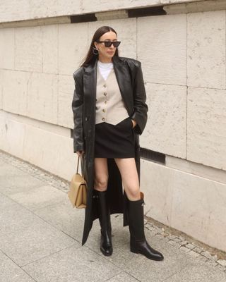 Influencer in knee high boots with buckles and mini skirt and cardigan