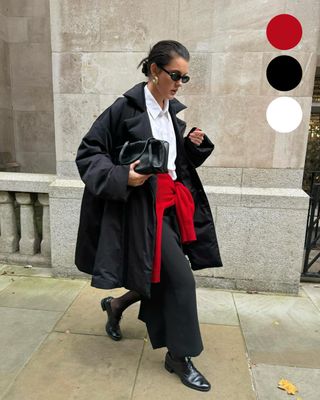 girl wearing a black coat, white shirt and black trousers with a red jumper tied around her waist