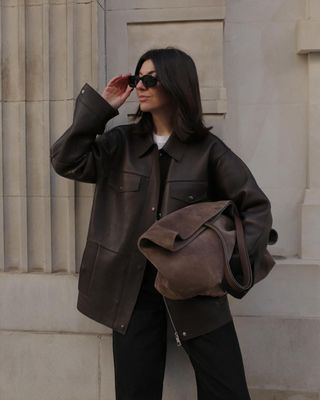 Francesca Saffari in leather jacket, black trousers and Arket brown suede bag.