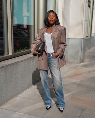 Ama Godson in a blazer, white tank top, and jeans.