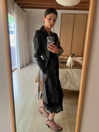 Woman wears a vintage faux leather trench coat, Sandro velvet slip dress and Neous kitten heels.