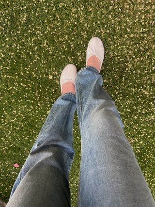 Woman walks in the grass in Jamie Haller jeans and Jamie Haller white ballet flats.