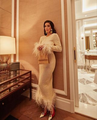 @bettinalooney wearing a white beaded dress with fur trim