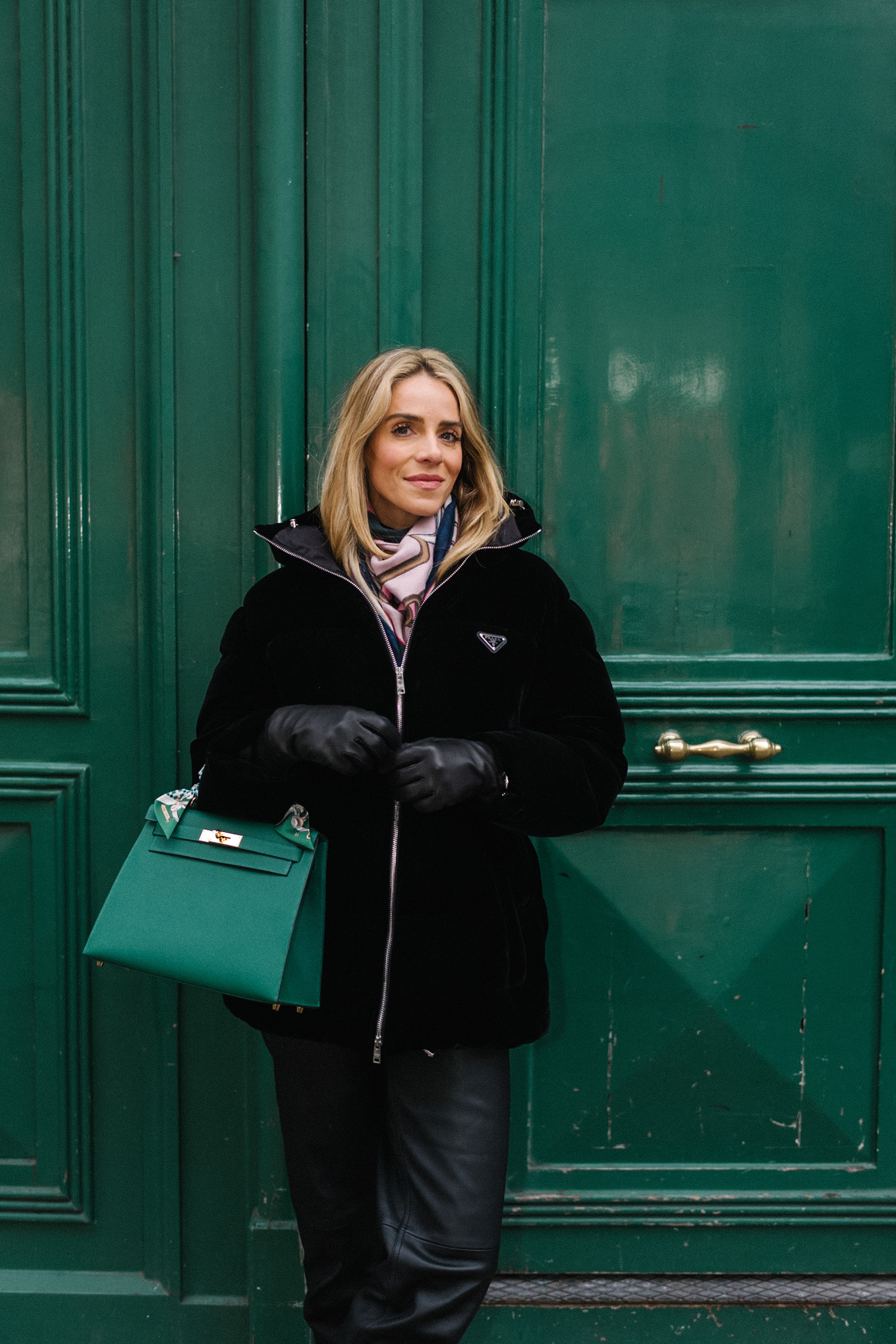 black velvet puffer coat black pants green handbag in paris