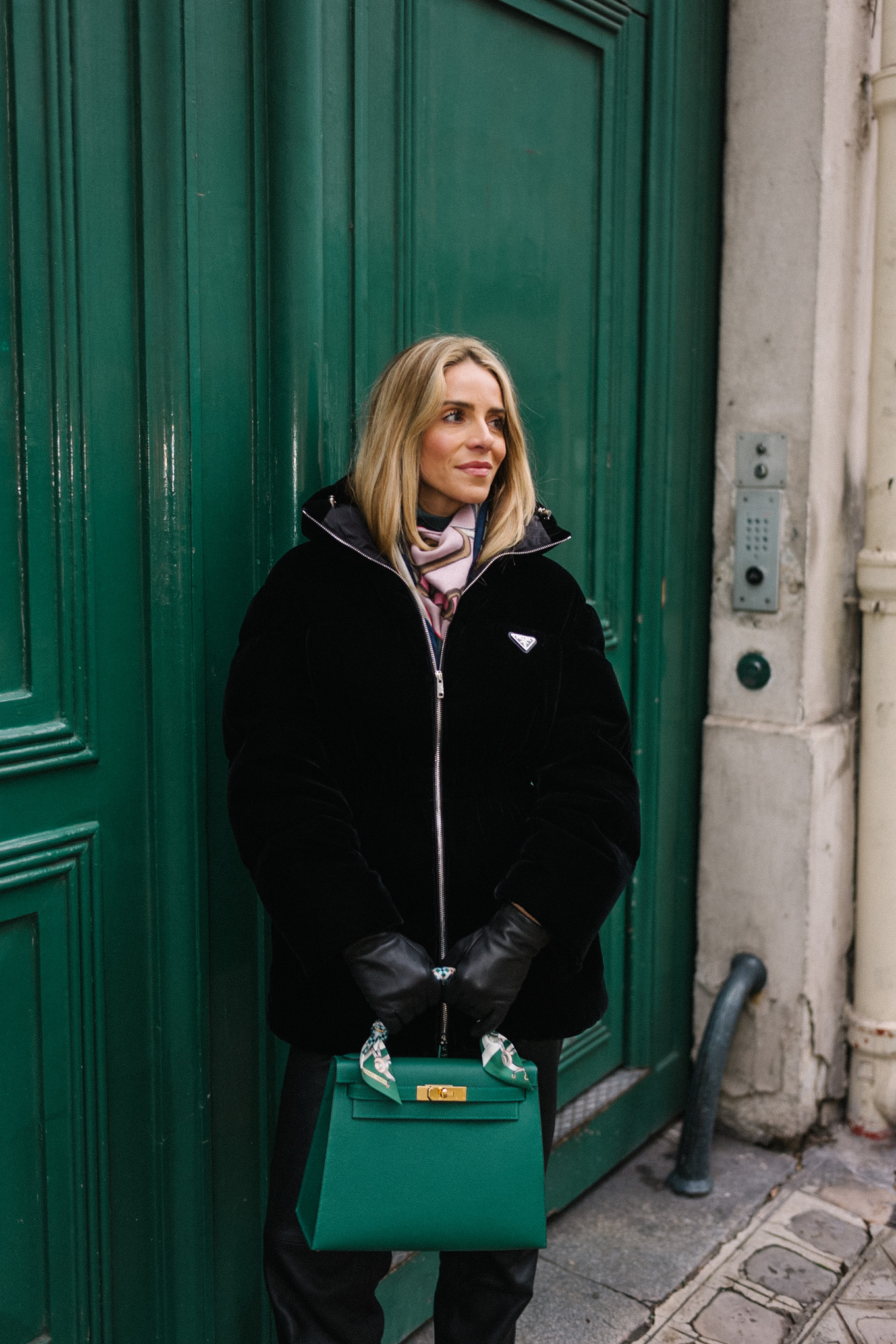 black velvet puffer coat black pants green handbag in paris