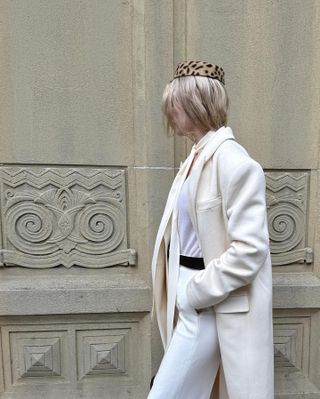 Woman wearing an animal print pillbox hat with an all-white outfit.