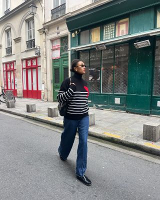 Woman wearing white shirt, blue jeans, brown trench coat and brown leather bag, walking on the streets of Paris.