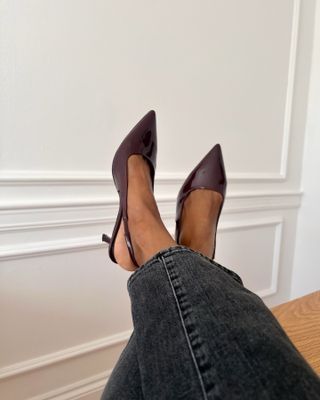 Woman wearing black jeans and burgundy leather slingback heels.