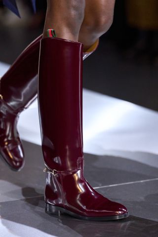 Glossy flat burgundy knee-high boots Gucci fall winter 2024.