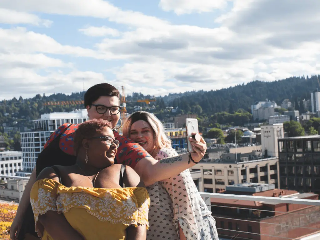 plus size black woman with short hair taking selfie with plus size woman with dark hair and plus size woman with blonde hair in front of a picturesque view