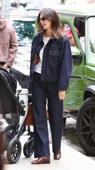 Kendall Jenner wears a denim jacket, white t-shirt, jeans, and The Row loafers in brown.