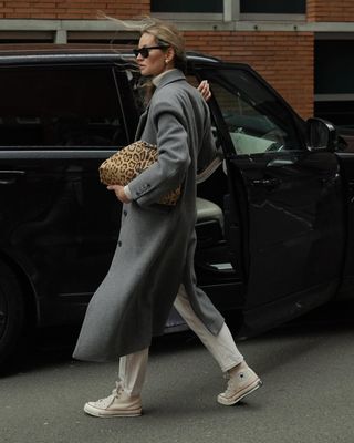 @anoukyve wearing white jeans, converse, long grey coat and holding a leopard print bag