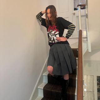 @alexachung wearing a pleated skirt, boots and band t-shirt