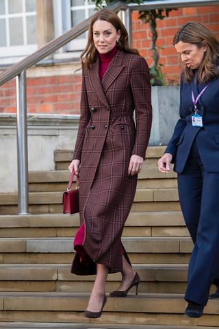 Kate Middleton wearing a brown plaid coat and burgundy turtleneck