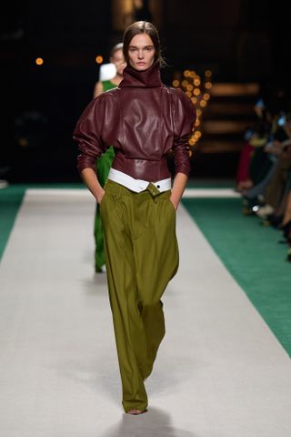 A Victoria Beckham model walks the spring/summer 2025 runway in trousers with a folded-over waistband.