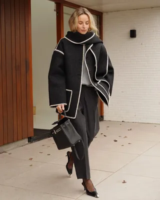 Woman wearing black Toteme contrast-stitch scarf coat, black pants, black bag and grey shirt.