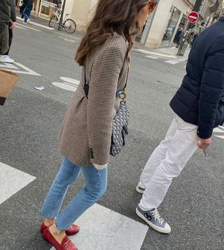 @leasy_inparis wearing light blue skinny jeans, a wool blazer and red loafers while crossing the road