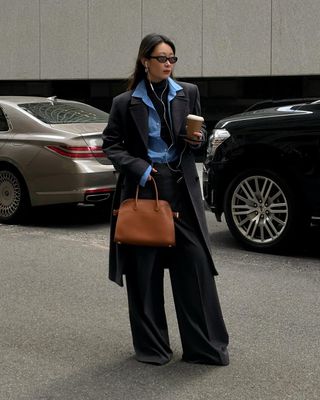 woman wears wool coat, shirt, tailored trousers