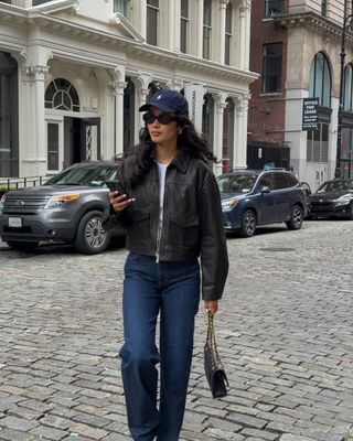 Woman wears leather biker jacket, black jeans and adidas sambas