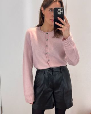 @streetchloe wears a baby pink cardigan with black leather shorts