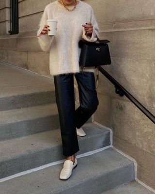 @dawn.tan wears cream loafers with black leather trousers, a cream jumper and a black handbag.