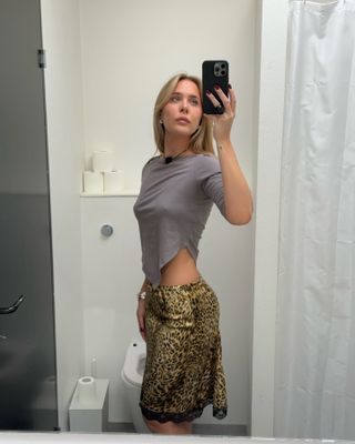 Karoline Beltner in a gray T-shirt and a leopard-print slip skirt.