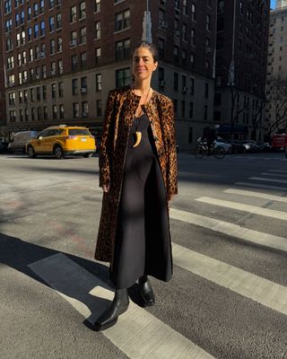 Leandra Cohen wearing a collarless leopard calf hair coat from By Malene Birger with a black maxi dress and black boots.