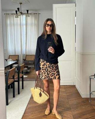 Anne-Laure Mais in a navy sweater and leopard print miniskirt.