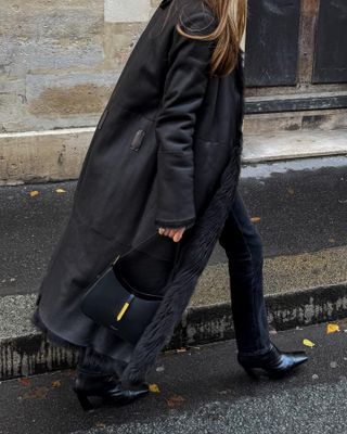 @saraloura wears black skinny jeans with a double-face fur coat and ankle boots while walking in the street